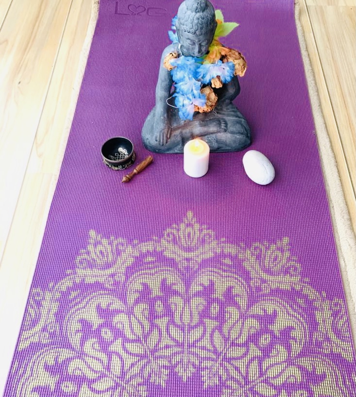 Buddha mit Kerze auf Yogamatte